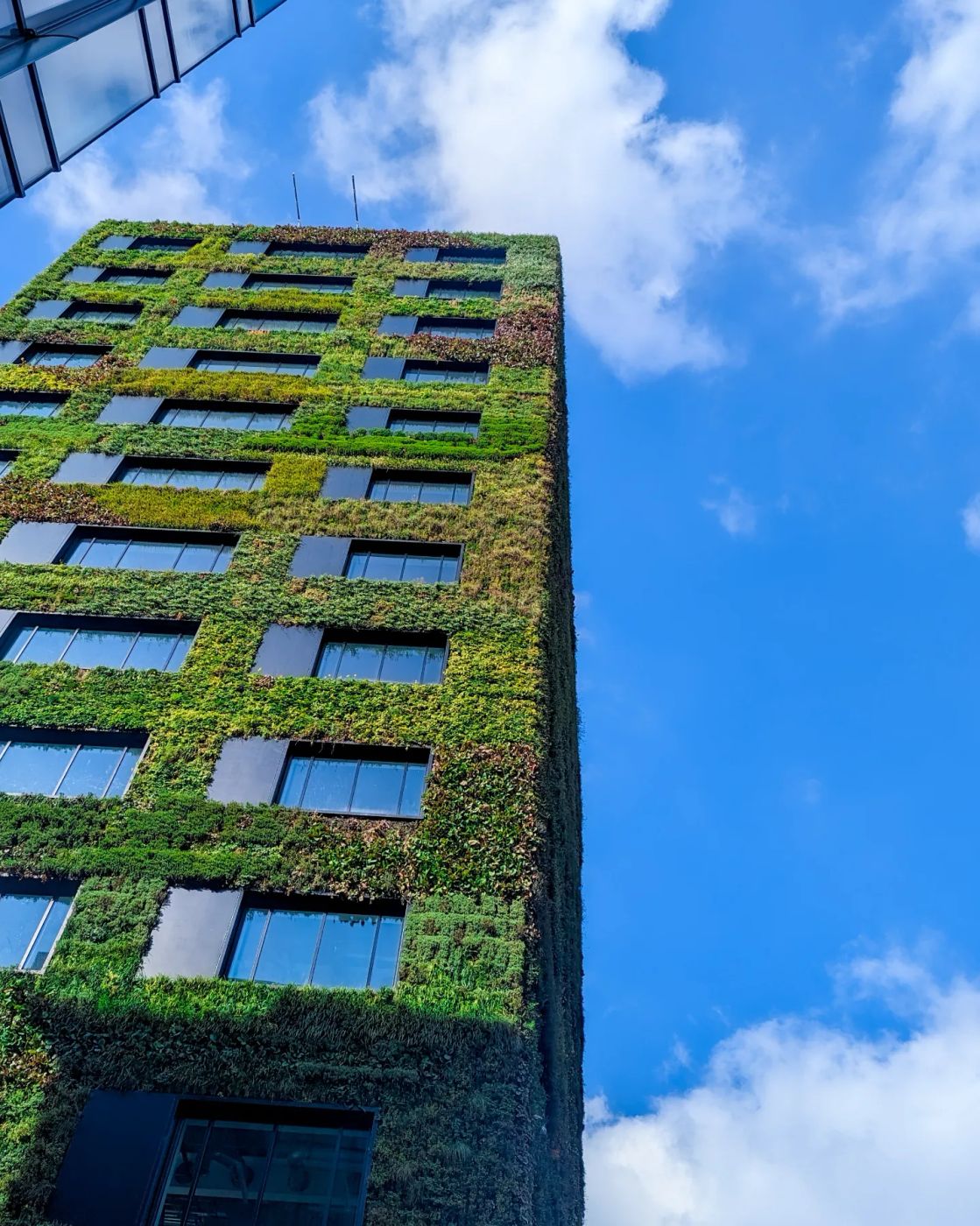 A tower clad in a green living wall of plants under a bright sky