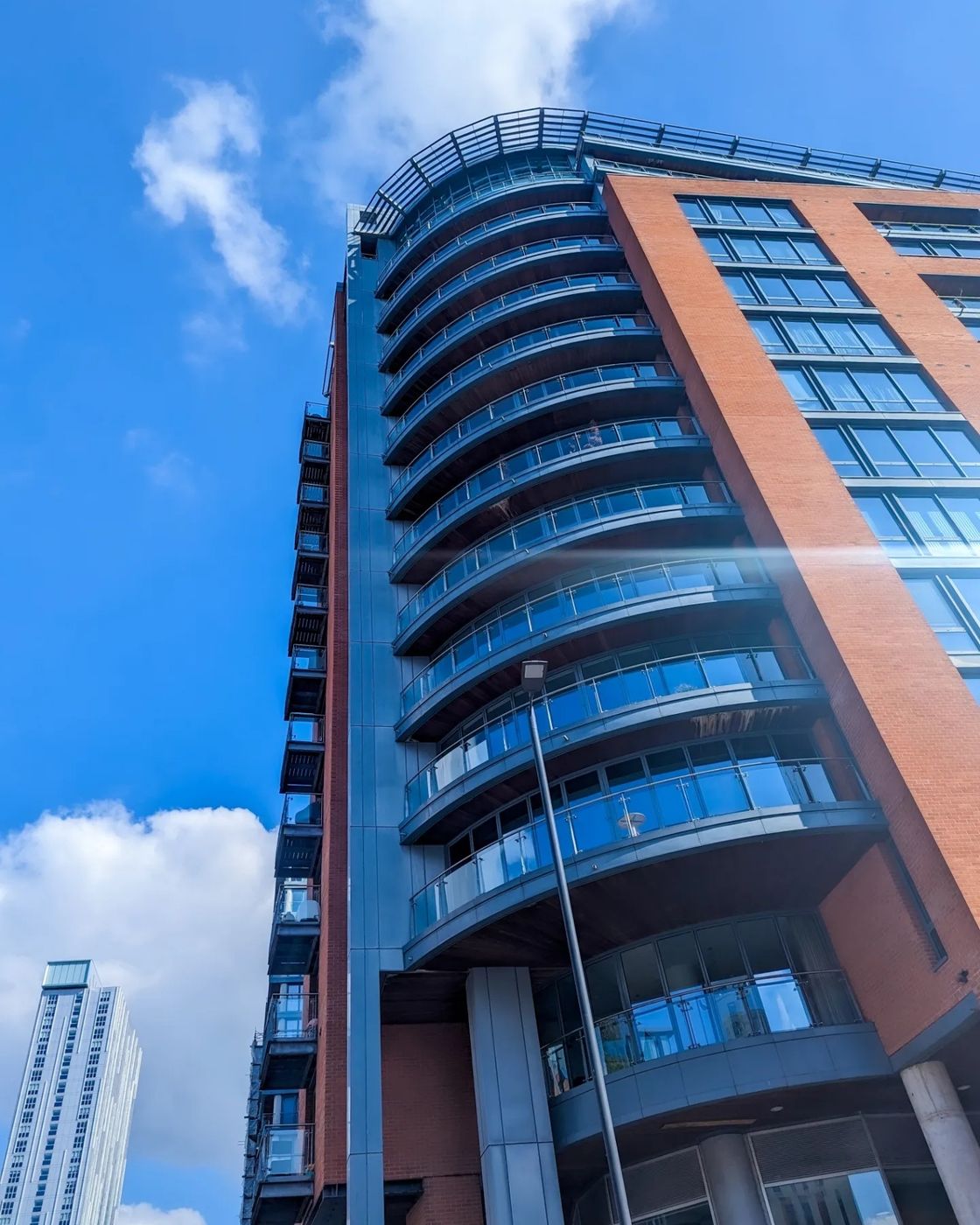 A brick apartment tower with a curved glass-balcony corner