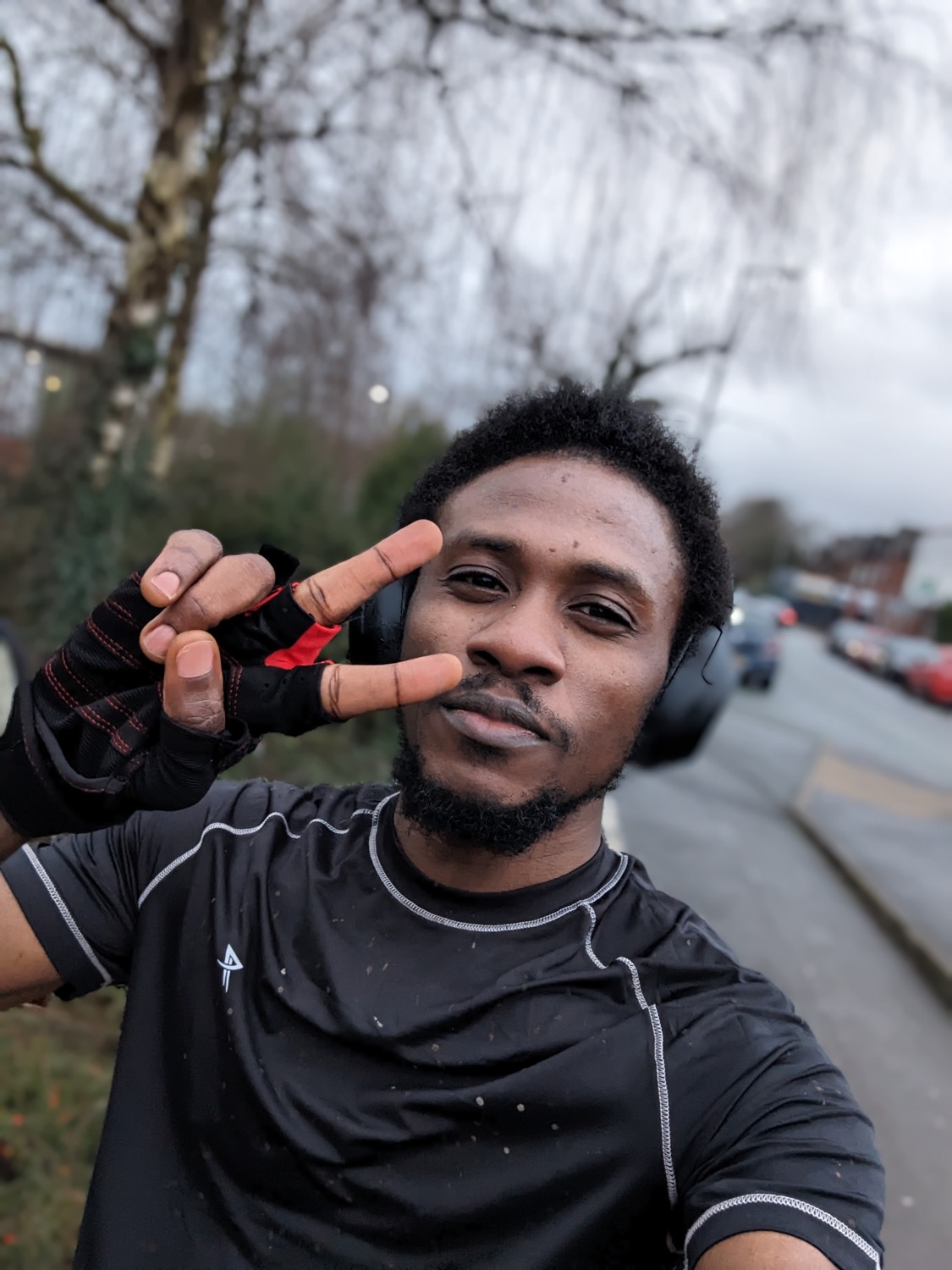 Me on a street after a ride, in cycling gloves and headphones, throwing a peace sign