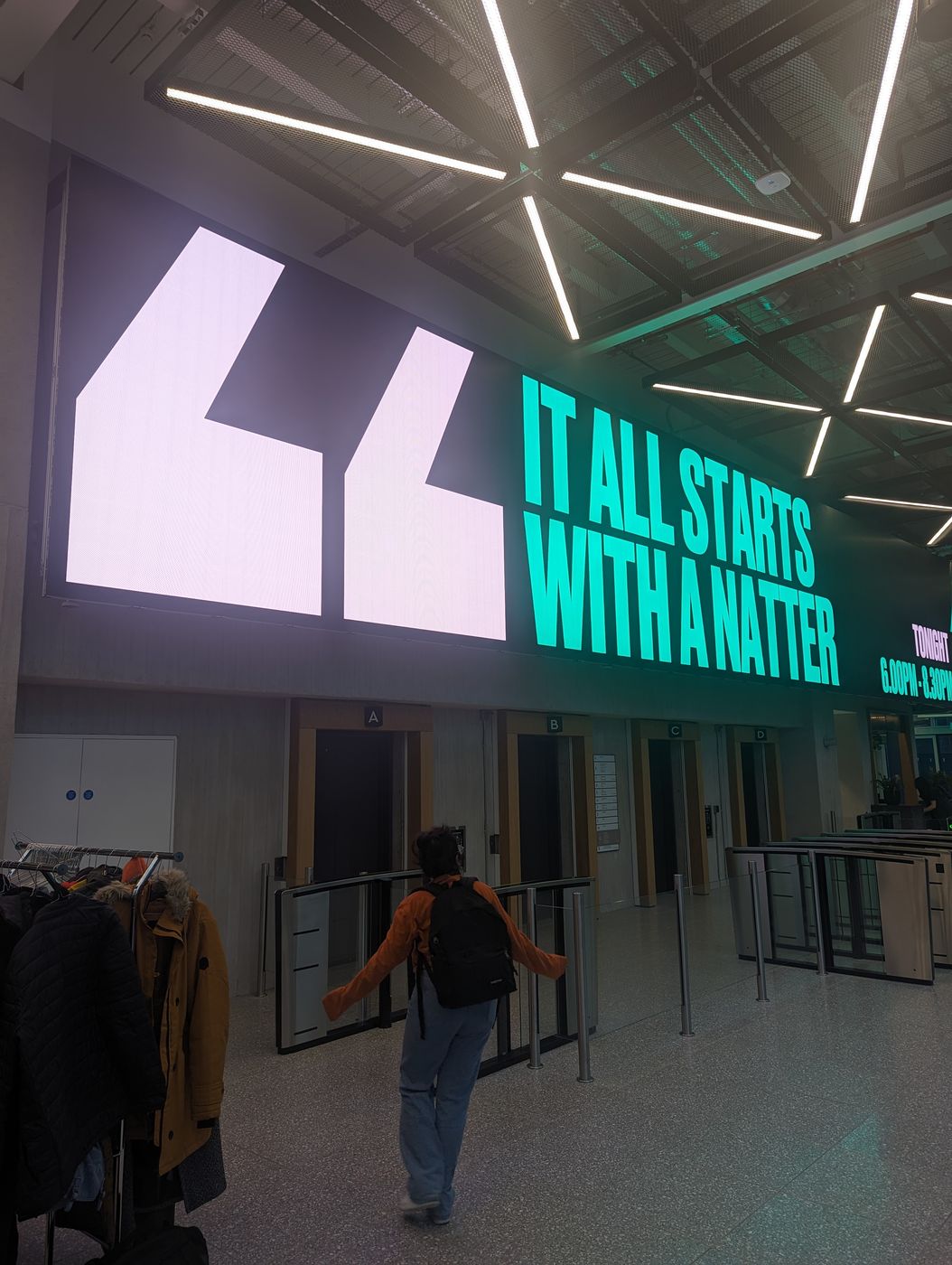 A design meetup venue with a giant LED wall reading: it all starts with a natter
