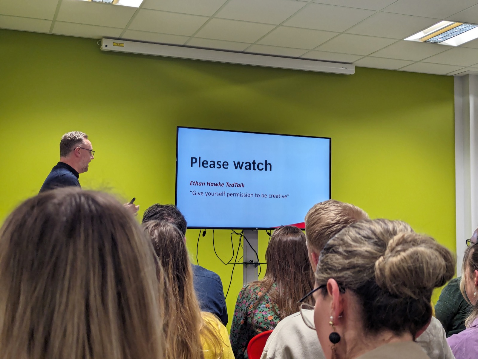 A speaker at a design meetup, screen reading: please watch the Ethan Hawke TED talk, give yourself permission to be creative