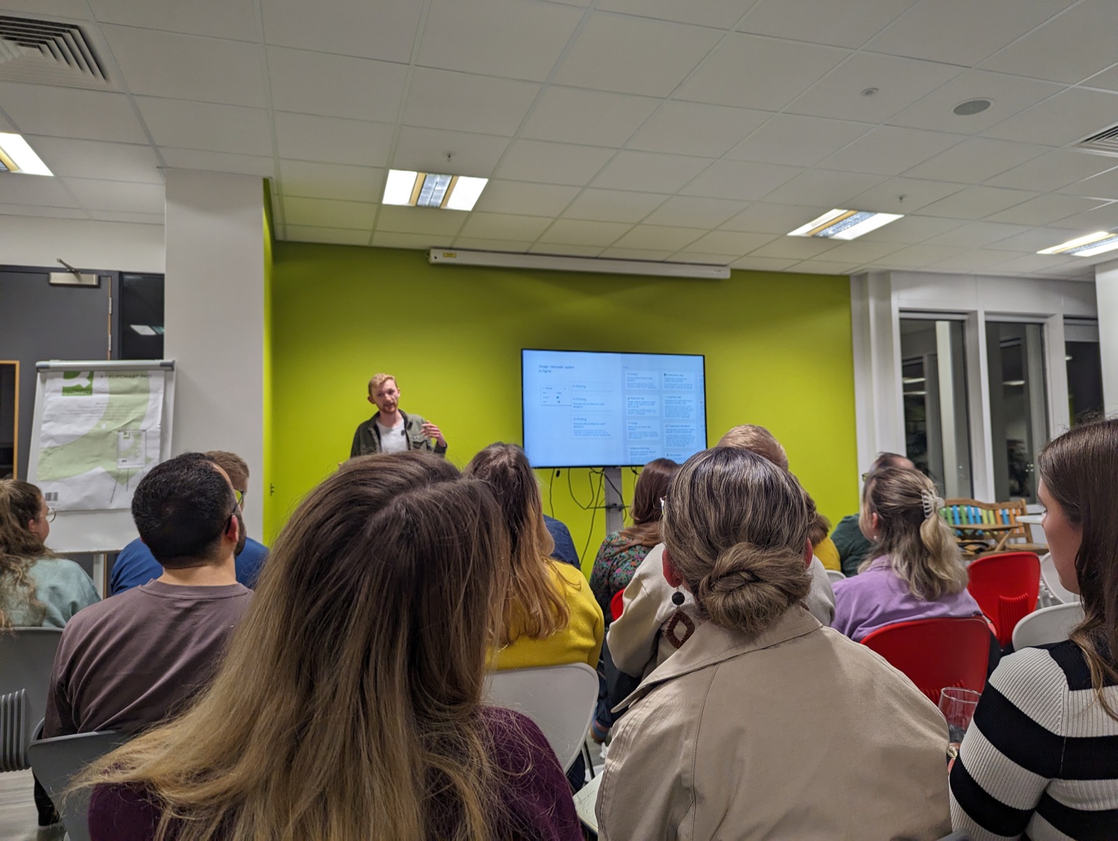 A speaker presenting a design rationale system built in Figma to a room at a design meetup